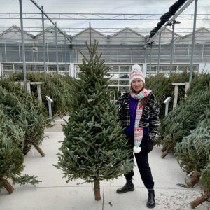 A fraser fir 6-7' tall is held up by a woman.