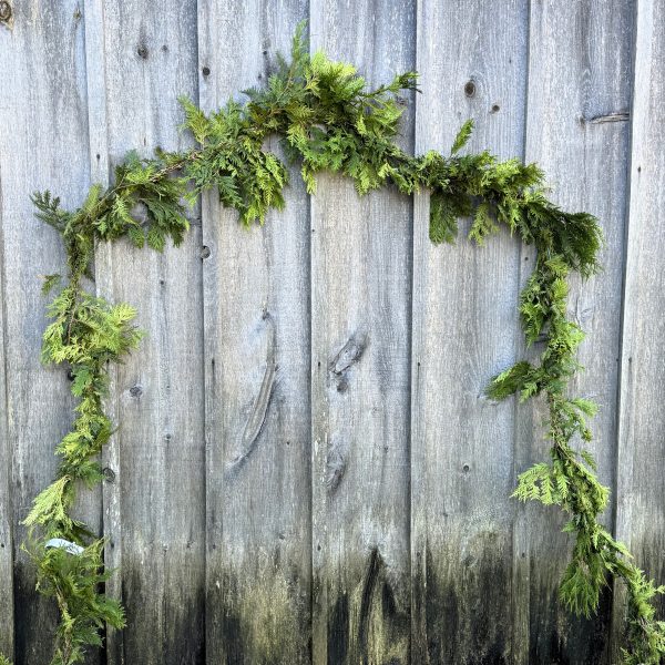 A length of natural cedar roping hangs on a weathered barn wall.