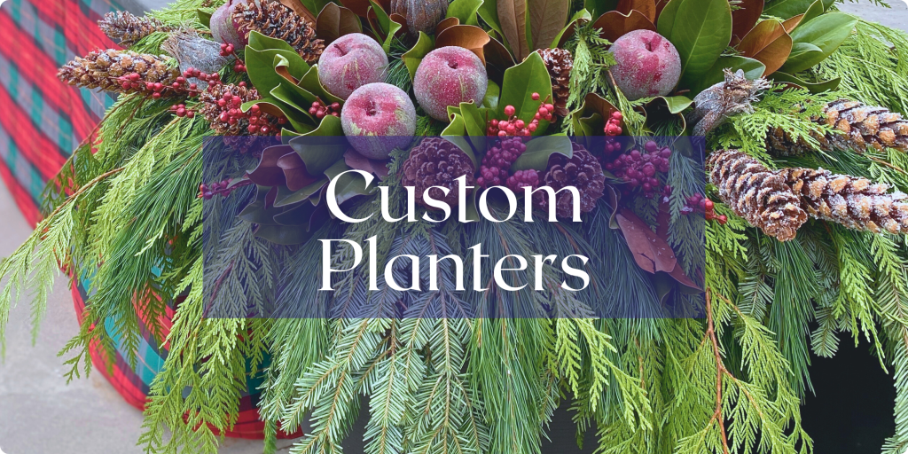 A planter filled with evergreens, pinecones, and assorted fruits is shown up close. Text: Custom Planters.